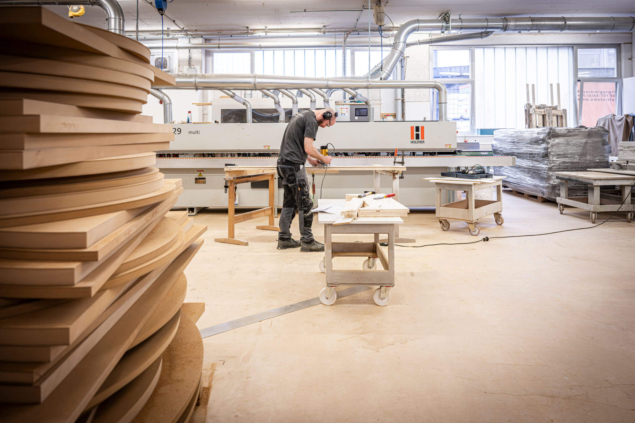 Blick in die Werkstatt der Schreinerei Goldinger mit Holzwerkstoffen, Maschinen und Mitarbeitenden bei der Fertigung von Schreinerarbeiten.