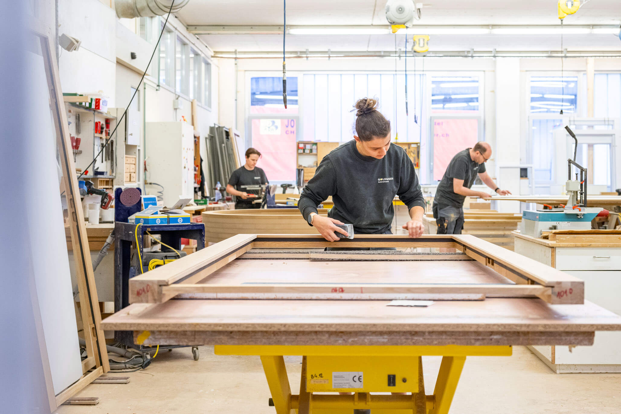 Mitarbeitende der Schreinerei Goldinger bei der Fertigung eines Schreinerprodukts in der Werkstatt.